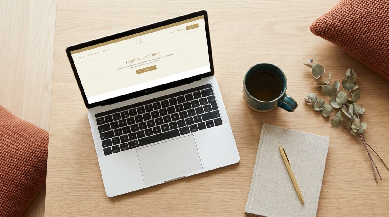 Ruhiger Schreibtisch von oben mit Laptop, Tee und Notizbuch, auf dem eine Website entsteht